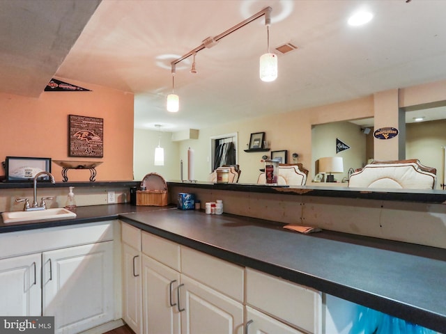 kitchen featuring track lighting, decorative light fixtures, sink, and white cabinets