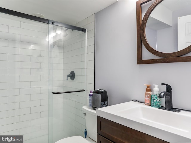 bathroom featuring vanity, toilet, and a shower with door