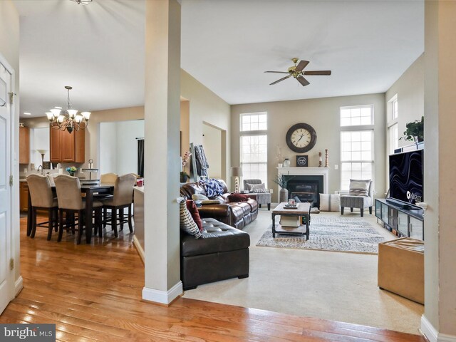 living room featuring ceiling fan with notable chandelier and light wood-type flooring