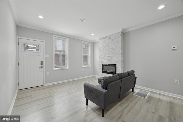 living room featuring a fireplace, crown molding, and light hardwood / wood-style flooring