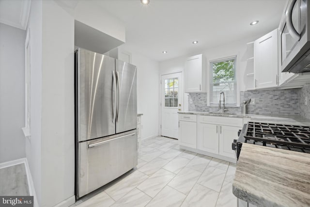 kitchen with light stone countertops, sink, stainless steel appliances, tasteful backsplash, and white cabinets