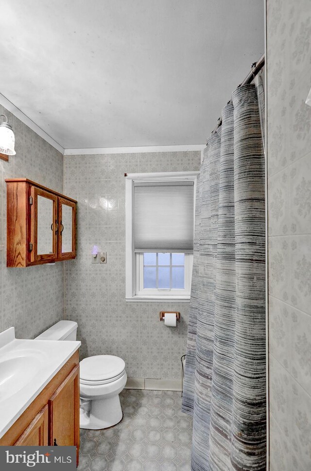 bathroom featuring vanity, toilet, ornamental molding, and tile walls