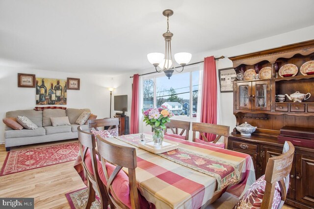 dining space with light hardwood / wood-style floors and a notable chandelier