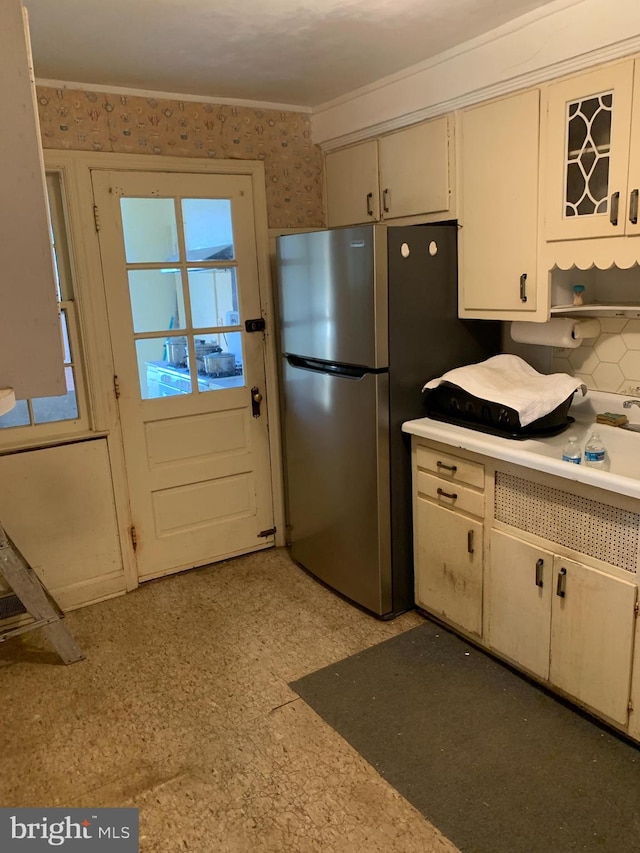 kitchen with tasteful backsplash, stainless steel refrigerator, and crown molding