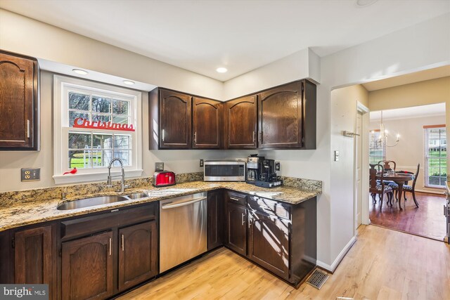 kitchen featuring an inviting chandelier, sink, light hardwood / wood-style flooring, light stone countertops, and appliances with stainless steel finishes