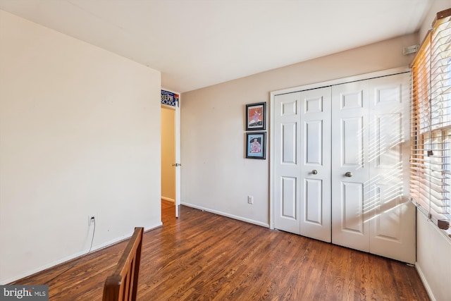 unfurnished bedroom with dark wood-type flooring and a closet