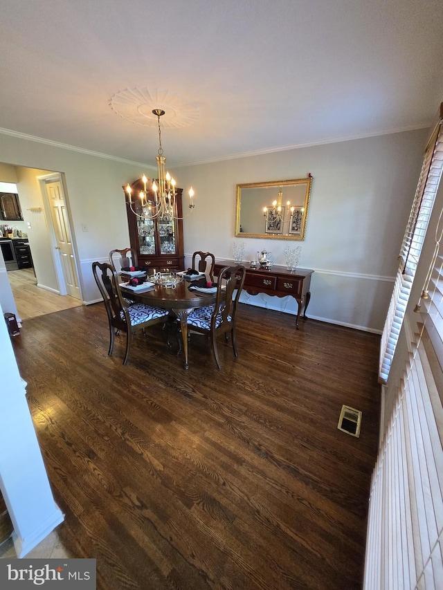 dining area featuring wood-type flooring, crown molding, and an inviting chandelier