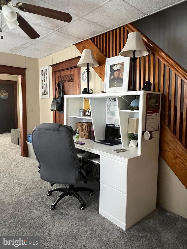 office space with ceiling fan, wooden walls, and dark colored carpet