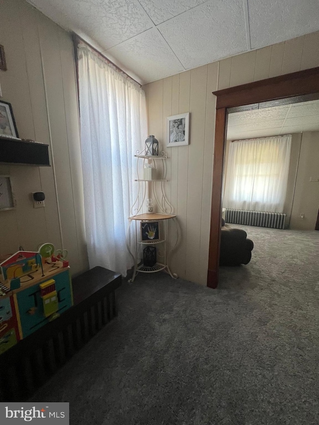 unfurnished bedroom featuring wood walls and dark carpet