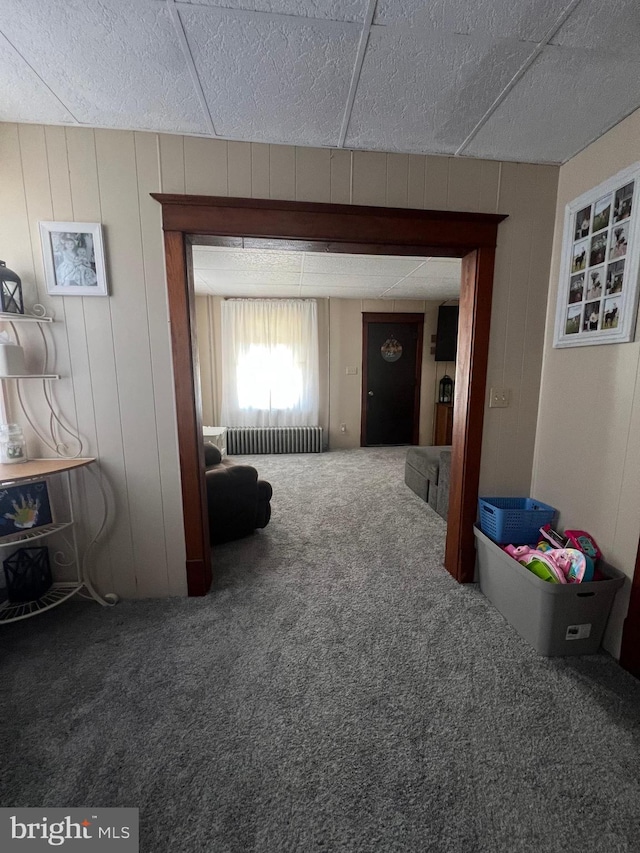 interior space with carpet, radiator, and wooden walls