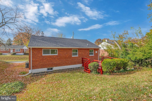 rear view of property with central AC unit and a yard