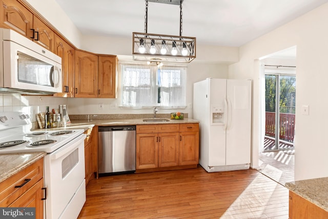 kitchen with a wealth of natural light, light hardwood / wood-style flooring, decorative light fixtures, and white appliances