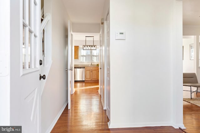 hall with hardwood / wood-style flooring, sink, and a chandelier