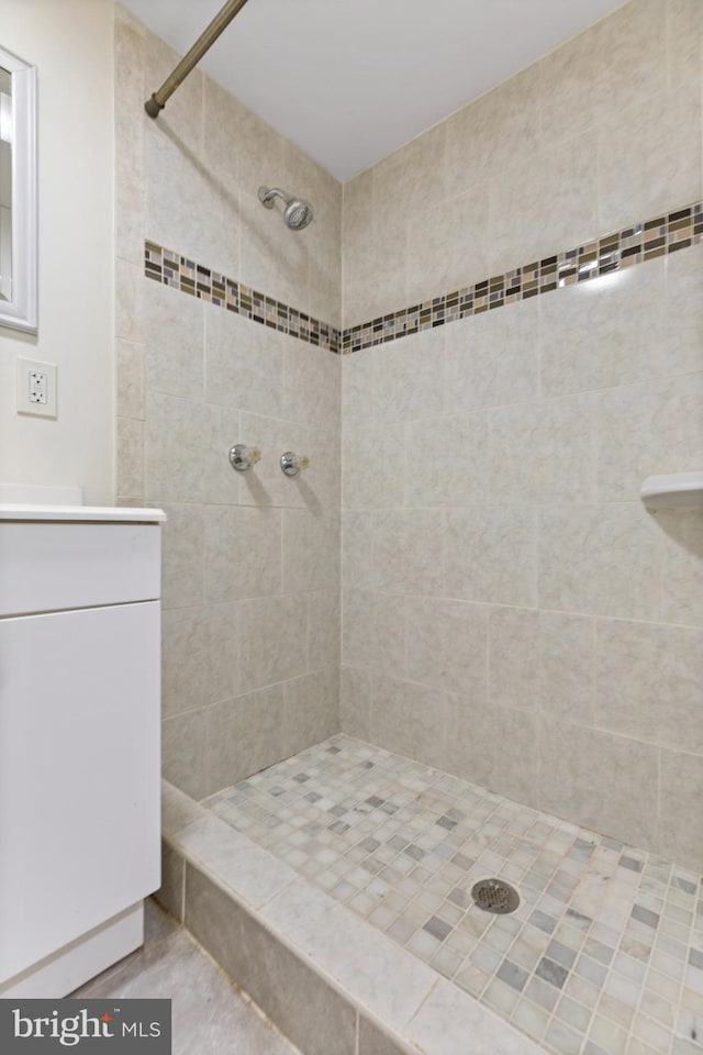 bathroom with tiled shower and vanity