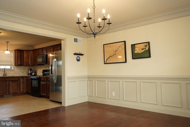 kitchen with tasteful backsplash, black appliances, decorative light fixtures, a notable chandelier, and hardwood / wood-style floors