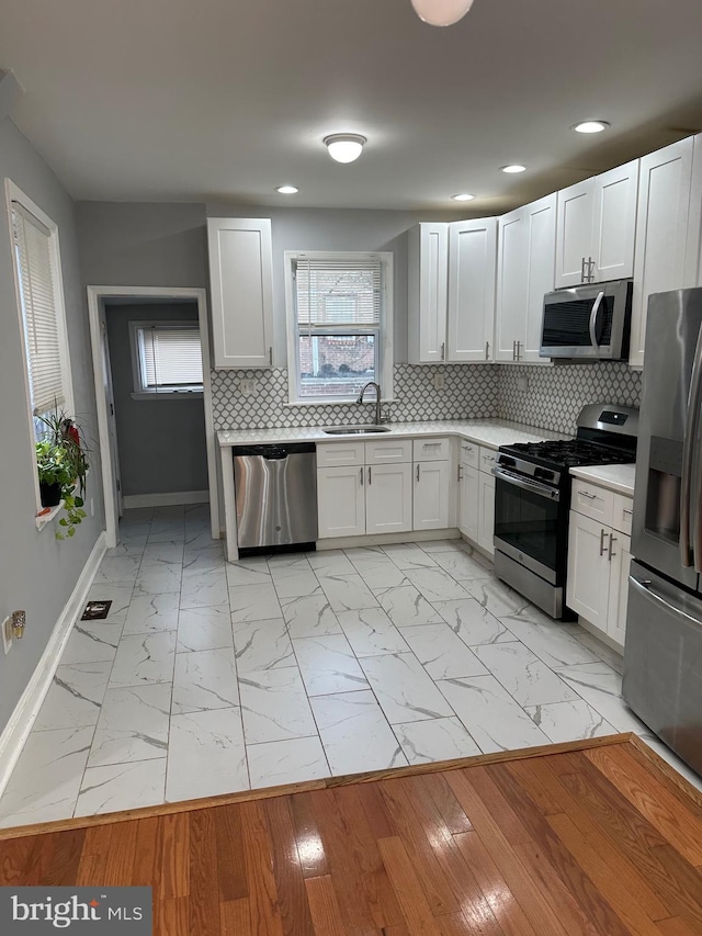 kitchen featuring marble finish floor, appliances with stainless steel finishes, light countertops, and a sink