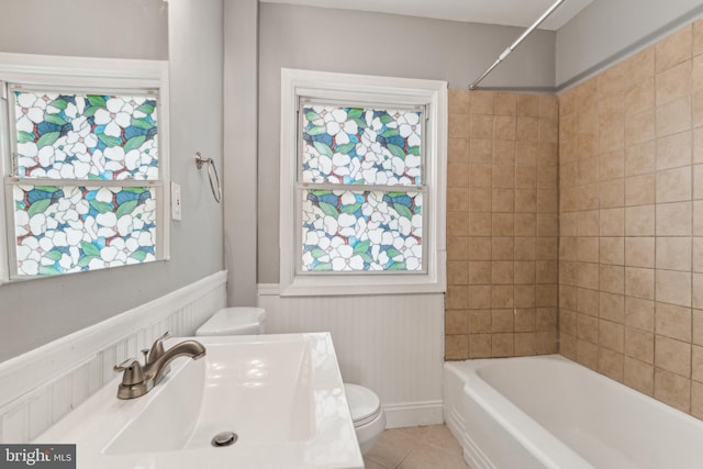 full bathroom featuring tile patterned floors, tiled shower / bath combo, toilet, and sink