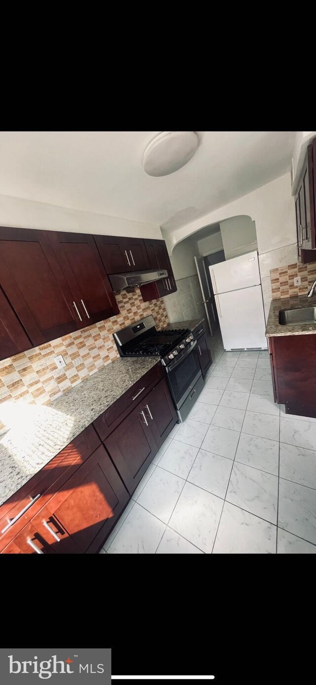 6412 Akron St, Philadelphia, PA 19149 - kitchen with freestanding refrigerator, gas range, a sink, under cabinet range hood, and decorative backsplash