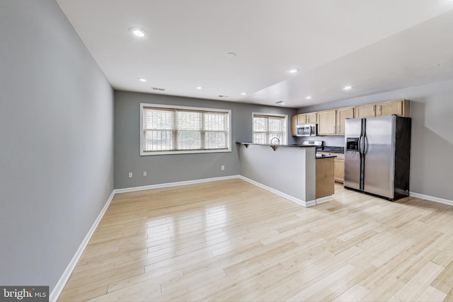 kitchen featuring kitchen peninsula, appliances with stainless steel finishes, light wood-type flooring, and light brown cabinets