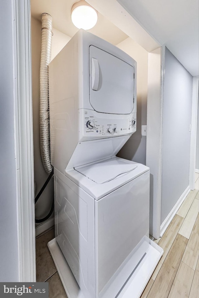 clothes washing area featuring stacked washer and dryer and light hardwood / wood-style flooring