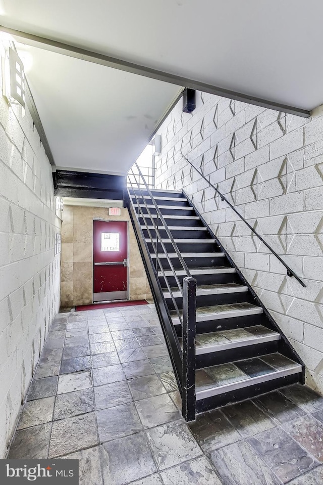 staircase featuring brick wall