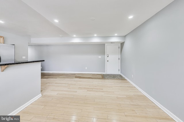 basement featuring white fridge and light hardwood / wood-style floors