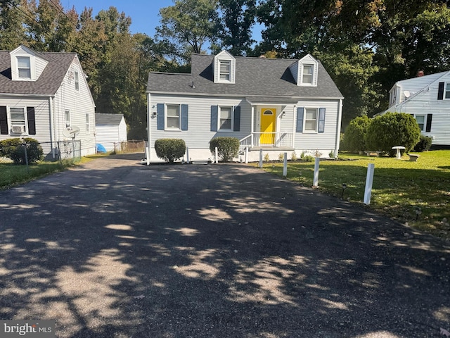 cape cod home featuring a front yard