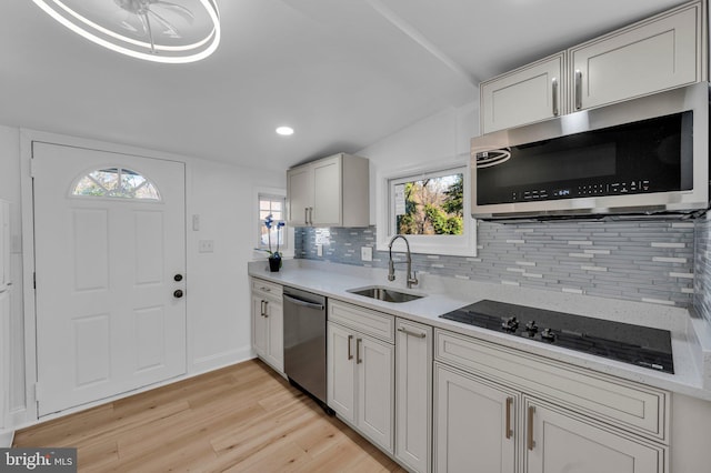 kitchen featuring lofted ceiling, sink, decorative backsplash, appliances with stainless steel finishes, and light hardwood / wood-style floors