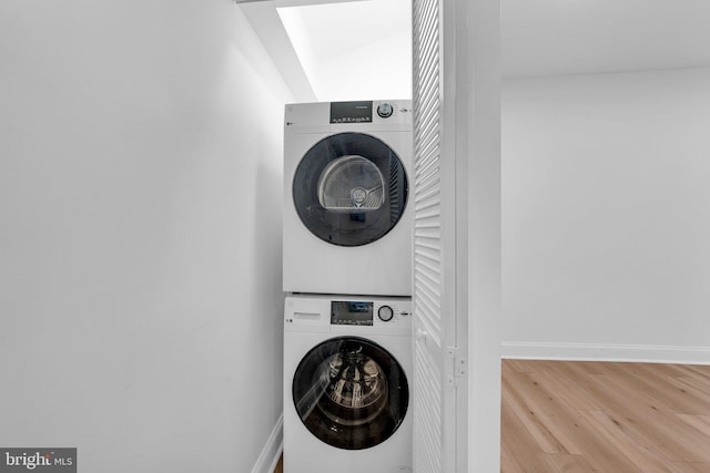 laundry area featuring wood-type flooring and stacked washer / dryer