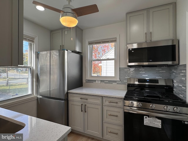 kitchen featuring a wealth of natural light, stainless steel appliances, light stone counters, and tasteful backsplash