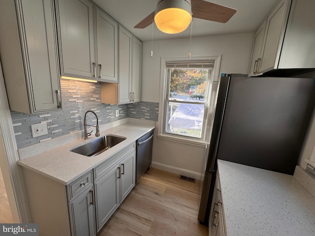 kitchen with light stone countertops, sink, ceiling fan, stainless steel appliances, and decorative backsplash