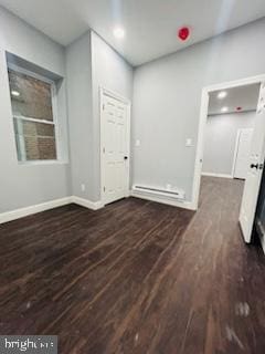 empty room featuring dark hardwood / wood-style floors and a baseboard heating unit