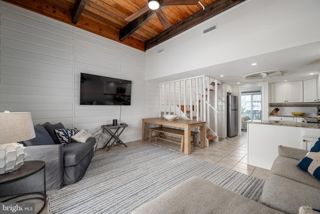 tiled living room with ceiling fan, a towering ceiling, beamed ceiling, and wooden ceiling