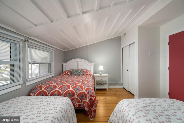 bedroom with hardwood / wood-style flooring, vaulted ceiling, and a closet