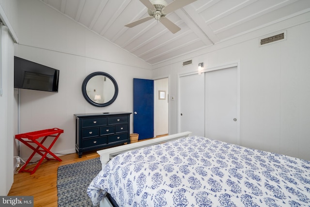 bedroom featuring vaulted ceiling with beams, ceiling fan, a closet, and hardwood / wood-style flooring