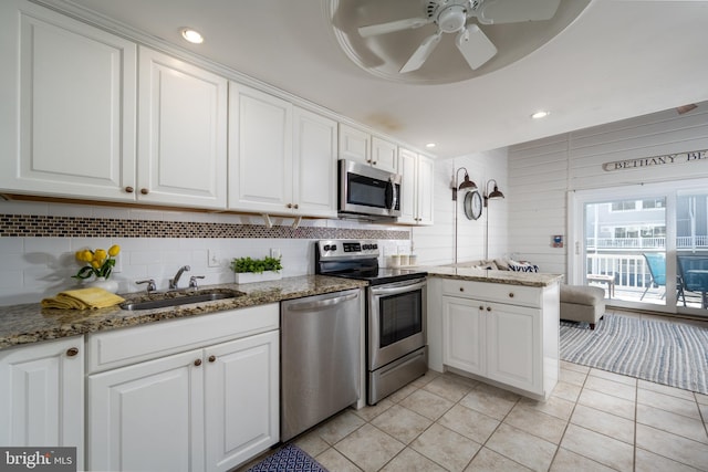 kitchen featuring white cabinetry, sink, stone countertops, light tile patterned flooring, and appliances with stainless steel finishes