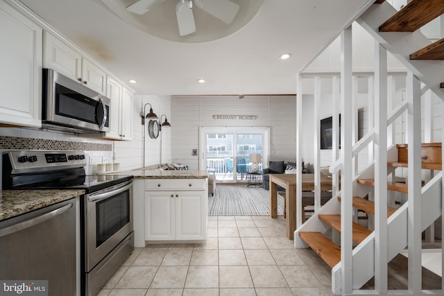 kitchen featuring white cabinets, dark stone countertops, light tile patterned floors, and stainless steel appliances