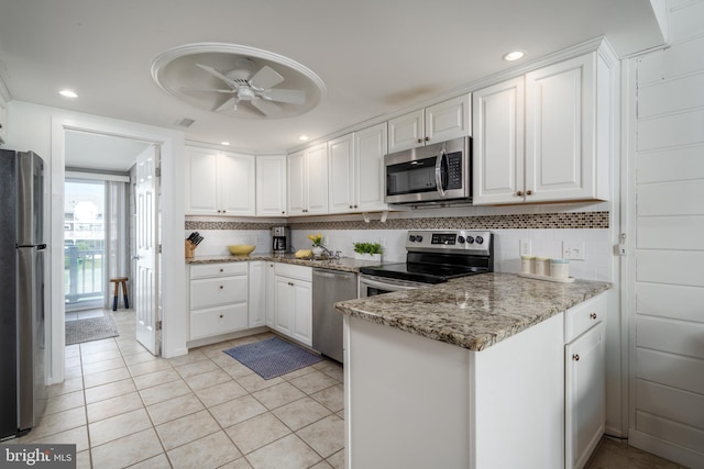 kitchen with white cabinets, appliances with stainless steel finishes, tasteful backsplash, and ceiling fan