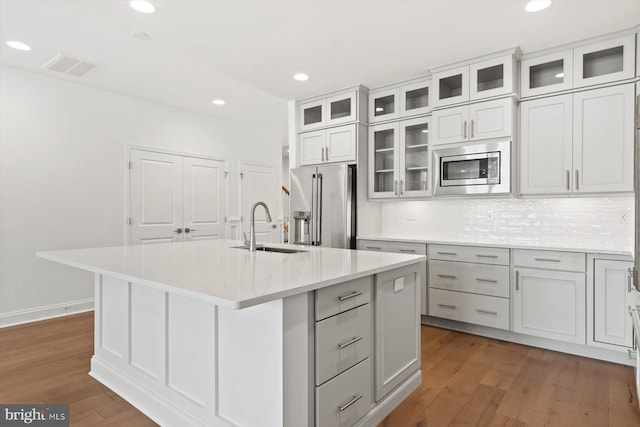 kitchen with a center island with sink, sink, stainless steel appliances, and dark wood-type flooring