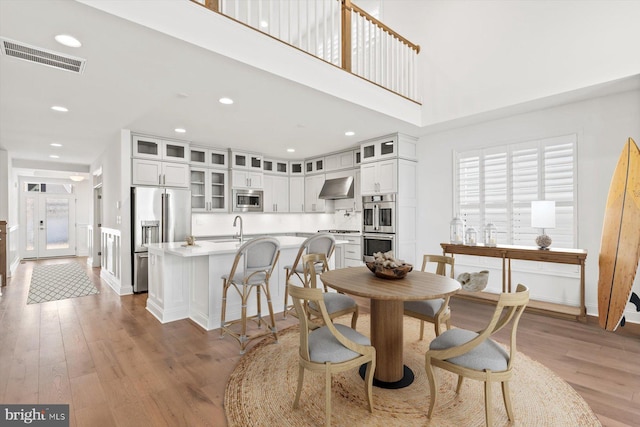 dining room with hardwood / wood-style floors, sink, and a high ceiling