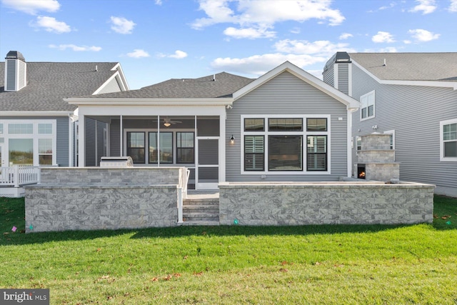 rear view of house with a sunroom, an outdoor stone fireplace, and a lawn