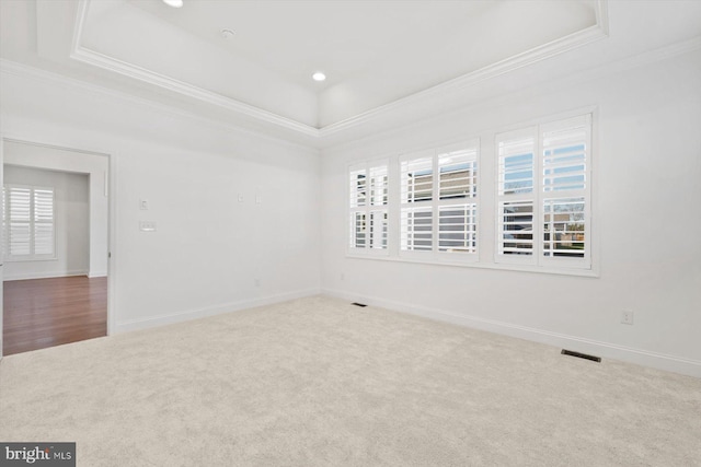 carpeted empty room with a tray ceiling and ornamental molding