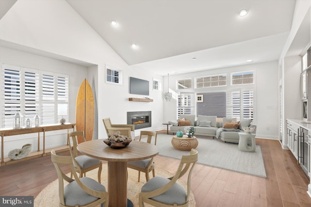 living room featuring light hardwood / wood-style floors, high vaulted ceiling, and plenty of natural light