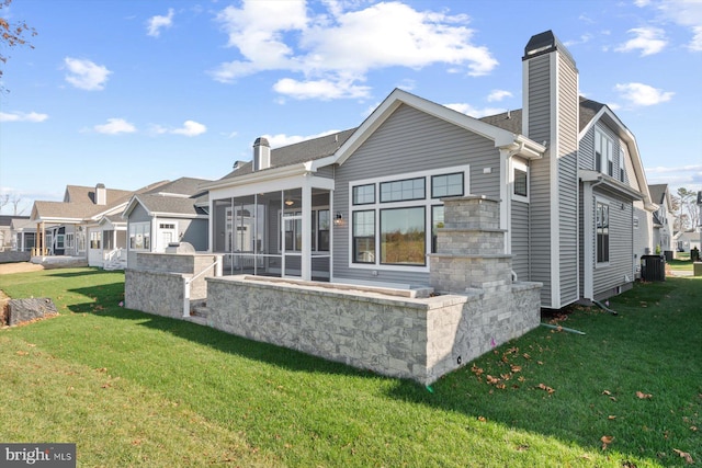 rear view of property featuring central air condition unit, a sunroom, and a yard