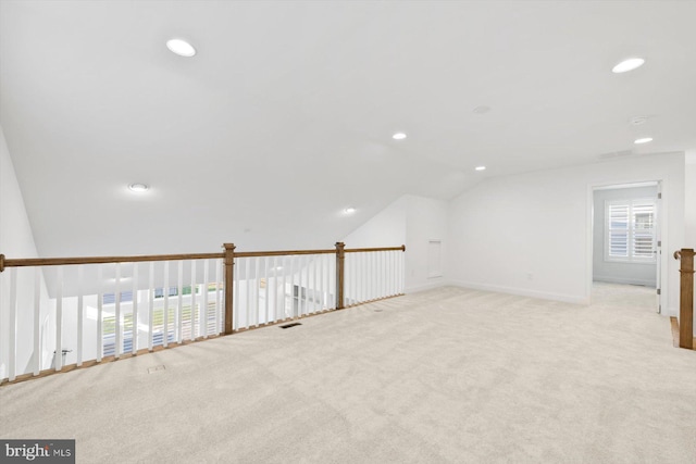 additional living space featuring light colored carpet and vaulted ceiling