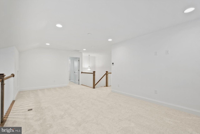 carpeted empty room with vaulted ceiling