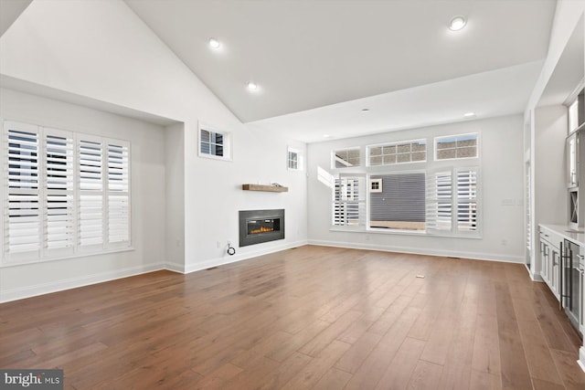 unfurnished living room featuring wood-type flooring and high vaulted ceiling