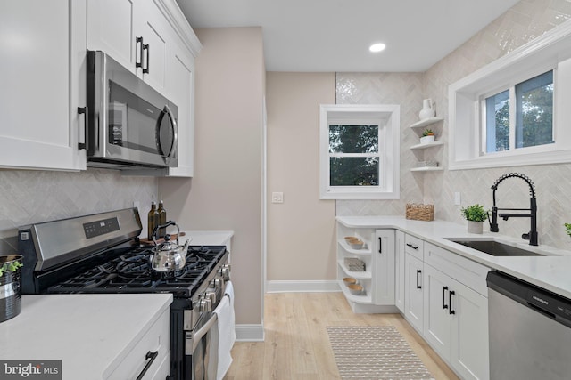 kitchen featuring light wood-type flooring, white cabinetry, sink, and appliances with stainless steel finishes