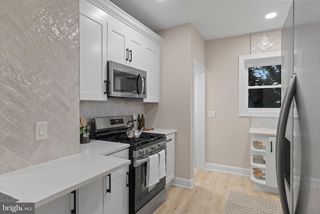 kitchen featuring light stone countertops, light wood-type flooring, white cabinetry, and stainless steel appliances