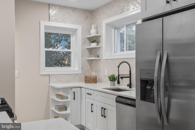 kitchen with decorative backsplash, stainless steel appliances, white cabinetry, and sink